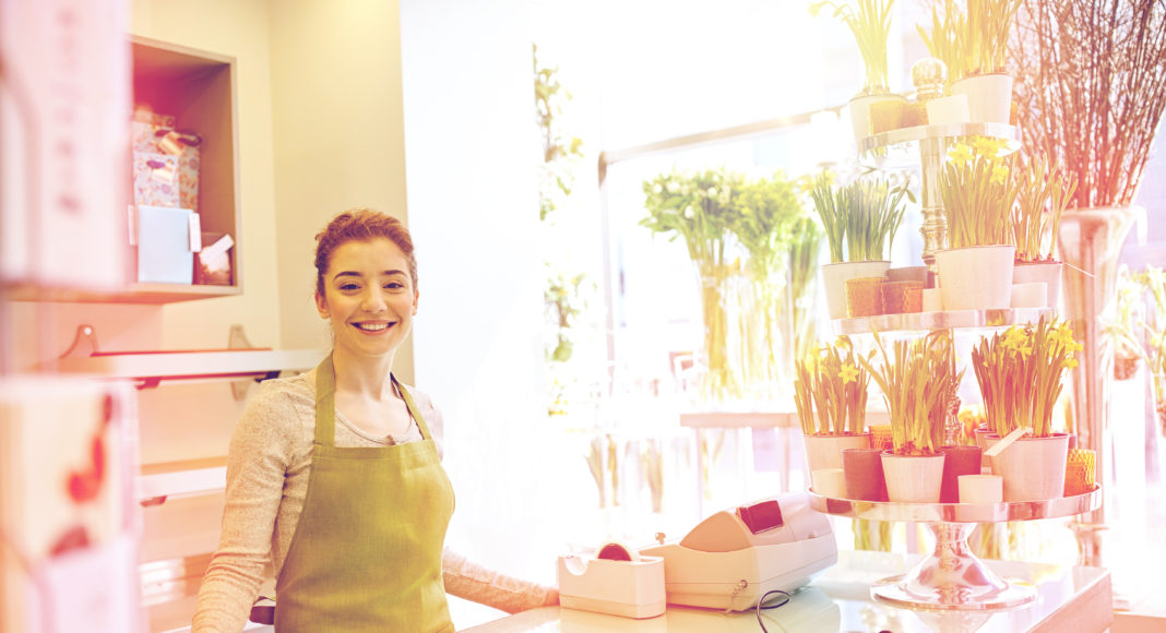 happy smiling florist woman at flower shop counter