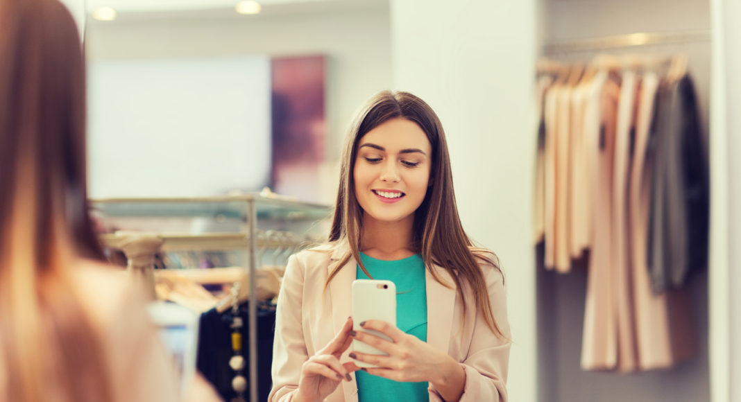 woman taking mirror selfie by smartphone at store